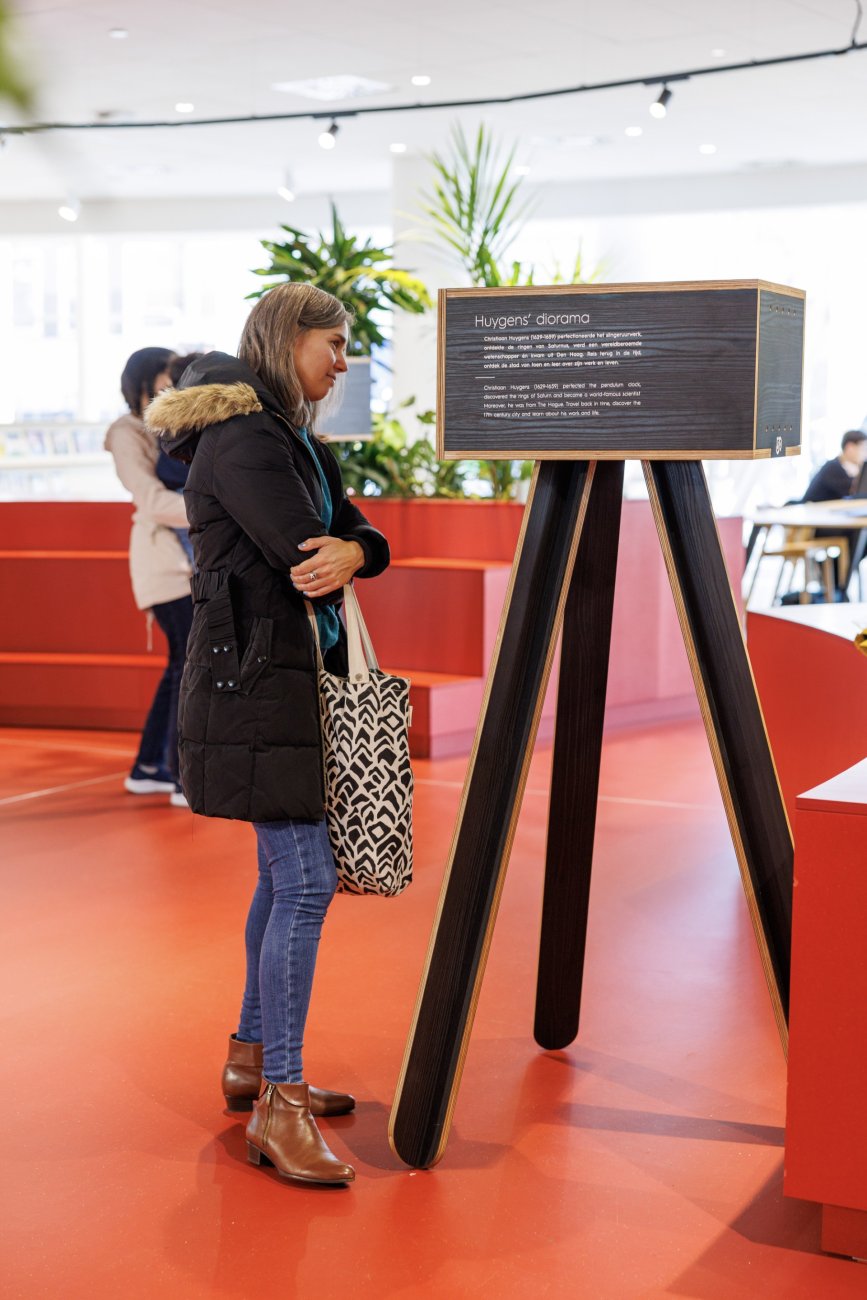 Een vrouw kijkt naar een kijkdoos van Huygens